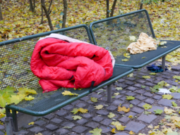 Roter Schlafsack einer wohnungslosen Person auf einer Parkbank